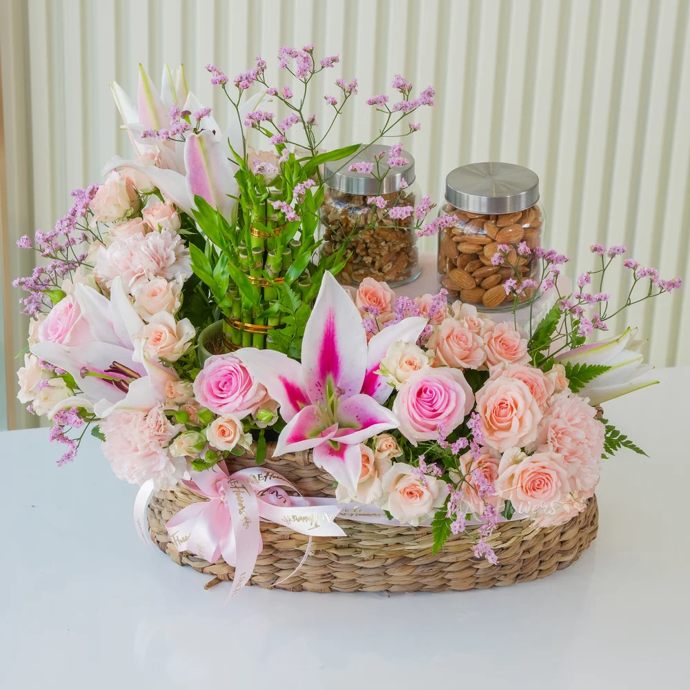 A basket arrangement of 250 Gms of Almonds, 250 Gms of walnut, 3 layer lucky bamboo, 2 pink lilies, 3 pink carnations, 5 pink roses and 4 pink spray roses with limonium fillers.