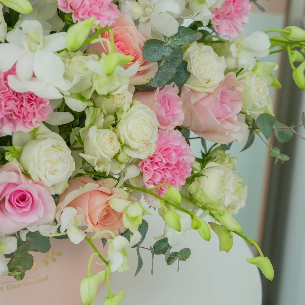A box arrangement of 20 white orchids, 12 pink roses, 12 pink carnations and 5 white spray roses with green fillers.
