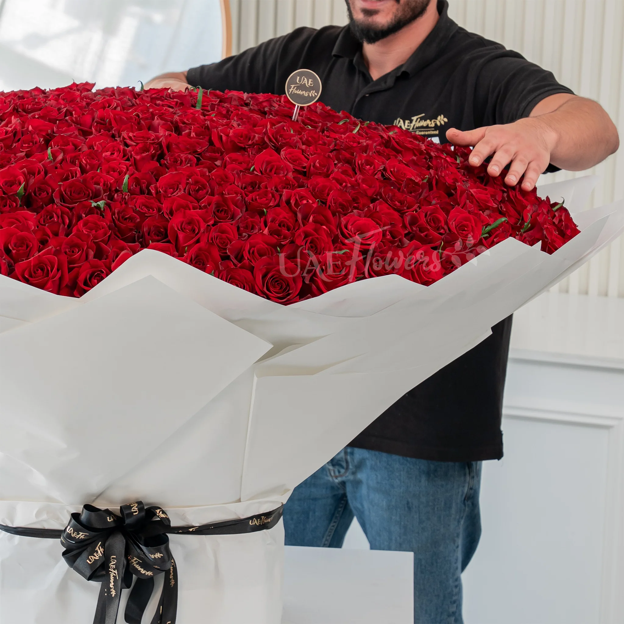 Bouquet of 1000 red roses in white wrapping paper tied with black ribbon.