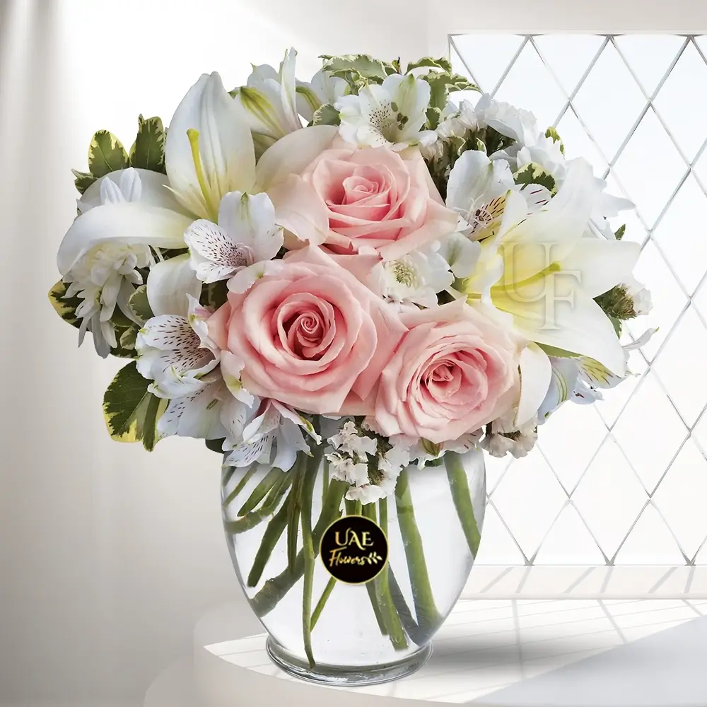 A bouquet of 3 white alstroemeria, 3 white crysanthemum, 1 white lilies & 8 peach roses in a glass vase
