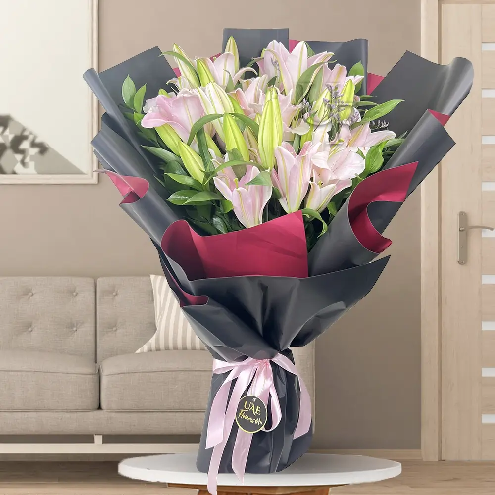 A bouquet of 10 pink lilies in black and red wrapping paper tied with a pink ribbon