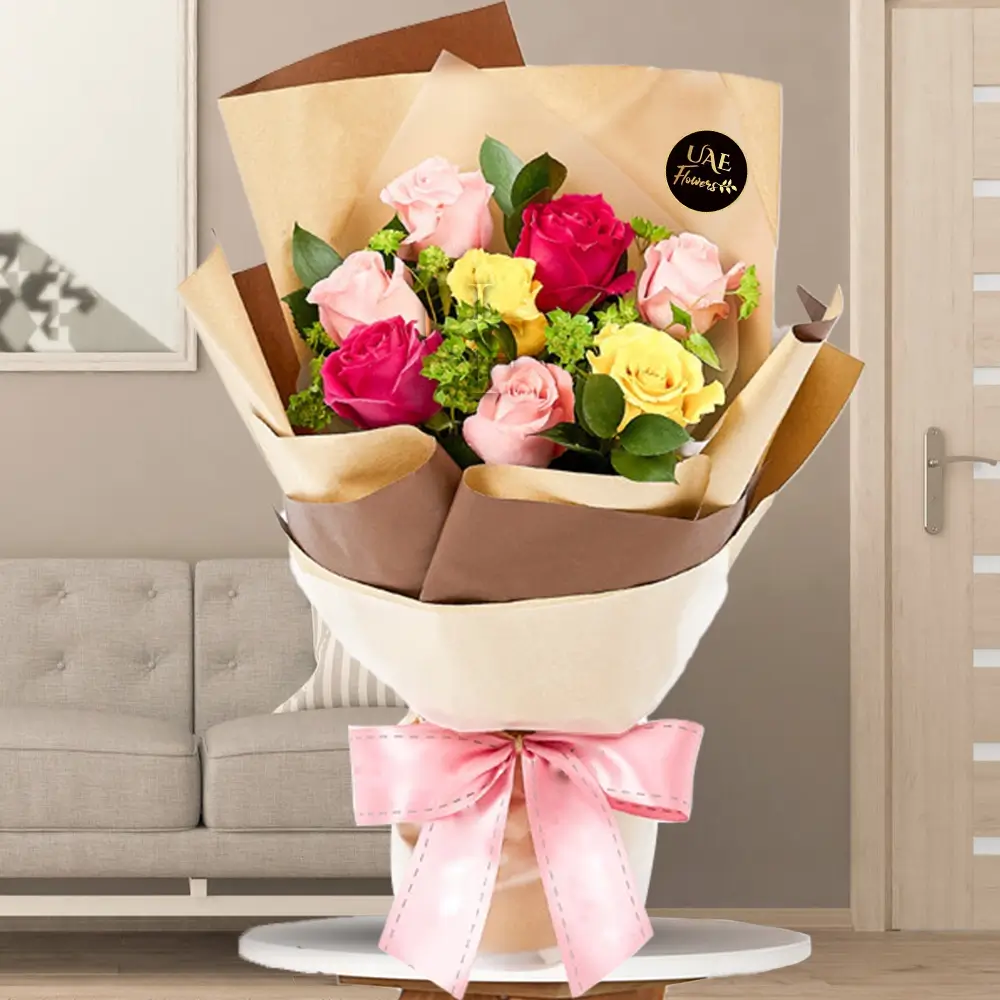 Bouquet of 8 mixed roses with bupleurum and ruscus leaves wrapped in brown and beige paper tied with a pink ribbon