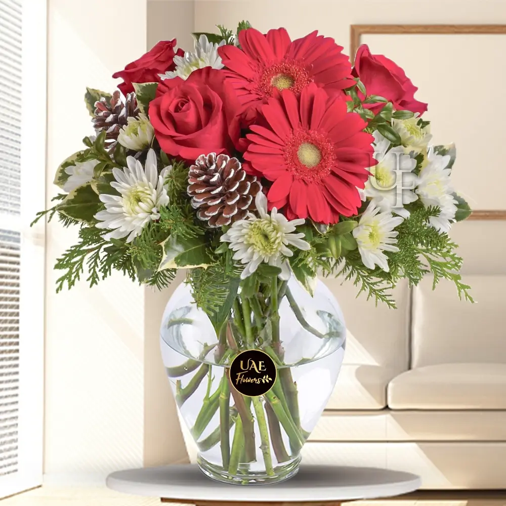 3 red gerberas, 5 red roses, 5 white spray chrysanthemums, with holly and assorted greens in a glass vase