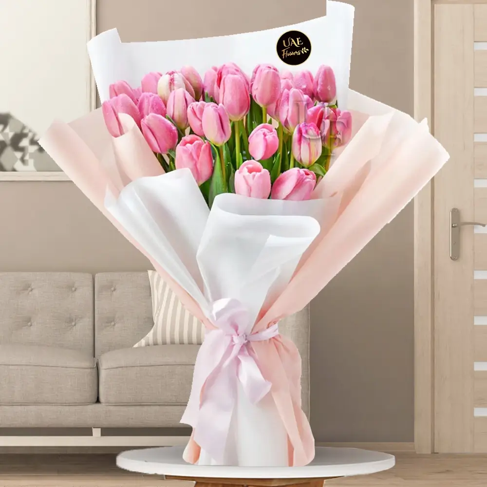A bouquet of 30 pink tulips with greens in a pink and white wrapping paper tied with pink ribbon