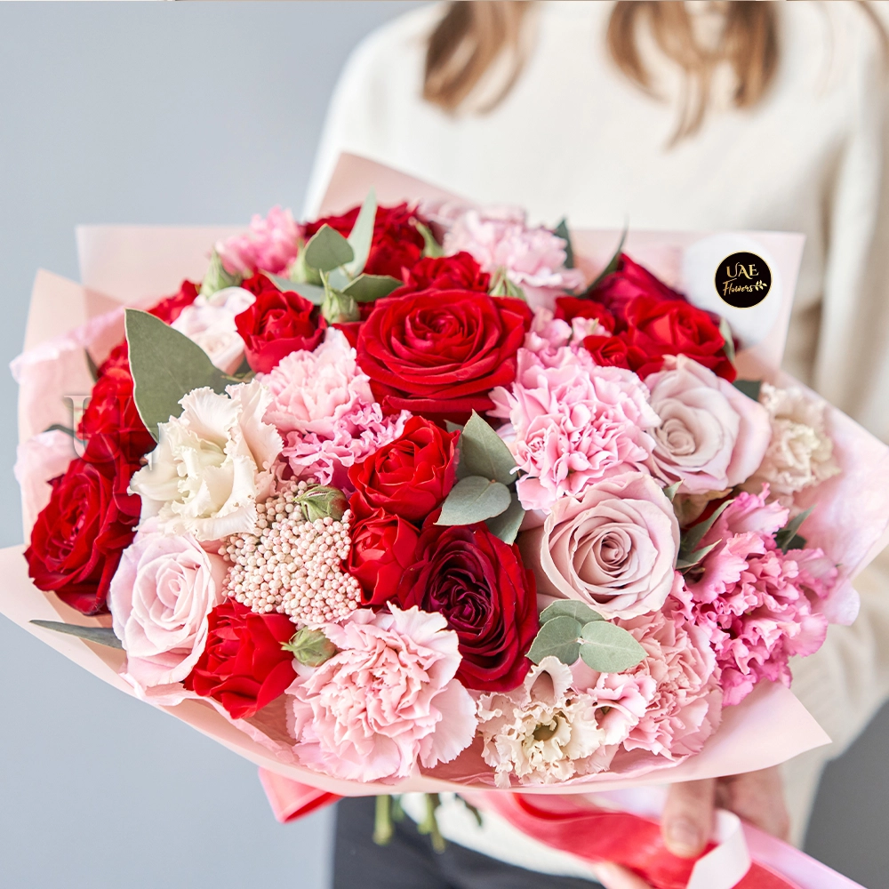 A bouquet containing 25 red and pink roses, 15 pink and white carnations with fillers, wrapped in pink paper, and tied with a red ribbon A bouquet containing 25 red and pink roses, 15 pink and white carnations with fillers, wrapped in pink paper, and tied with a red ribbon