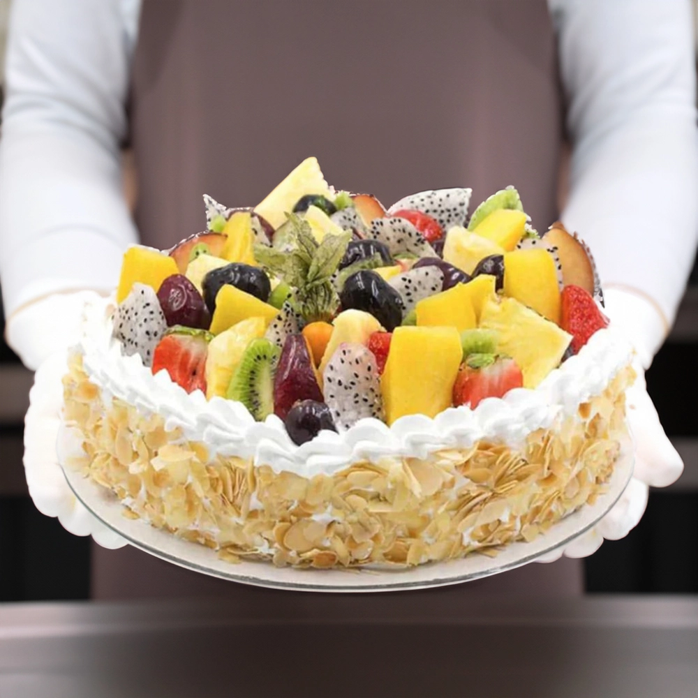 Fresh fruit cake topped with a variety of vibrant exotic fruits, including kiwi, dragon fruit, berries, and finished with almond flakes and whipped cream.