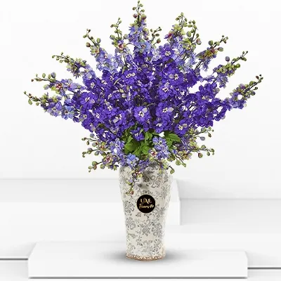 A bouquet of 15 blue delphinium with fillers in a vase