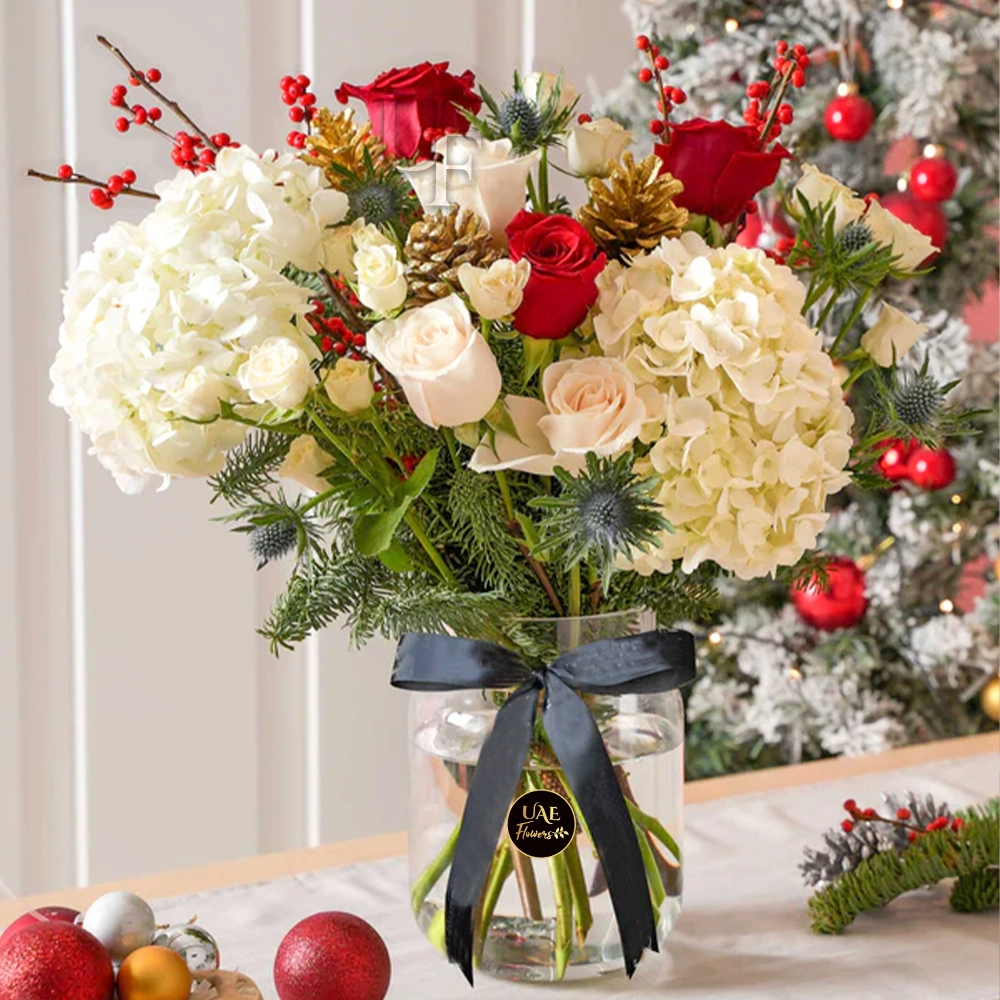 2 white hydrangeas, 10 red and white roses, 5 white spray roses, golden pinecone, winter berries and green fillers in a glass vase tied with black ribbon