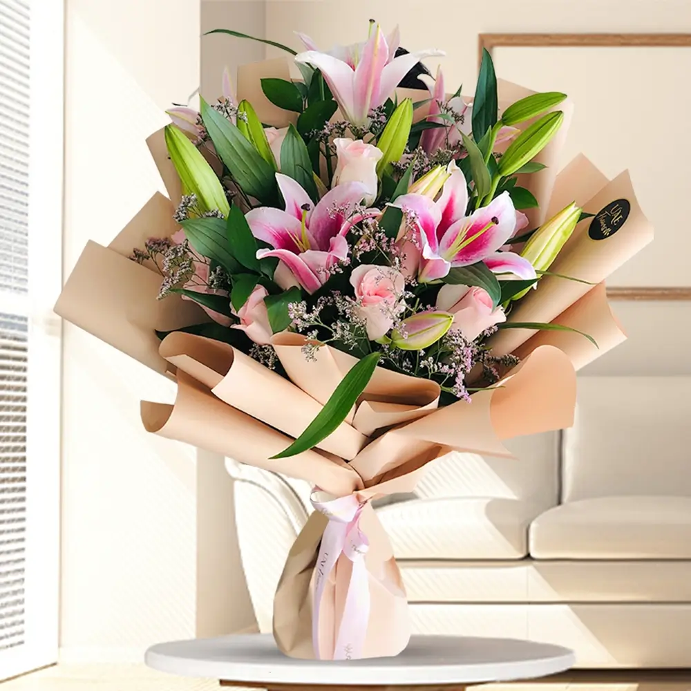 A bouquet of 3 pink lilies and 10 pink roses with fillers in brown wrapping paper tied with pink ribbon