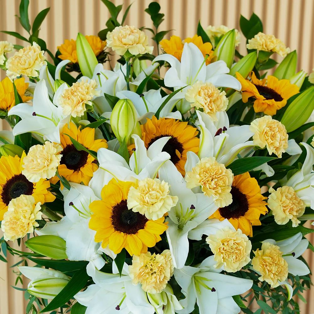 15 white lilies, 10 sunflowers & 20 peach carnations in a glass vase
