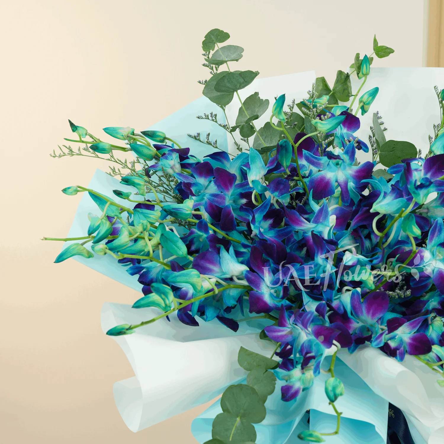 A bouquet of 20 blue orchids with greens and limonium fillers wrapped in blue and white paper tied with blue ribbons