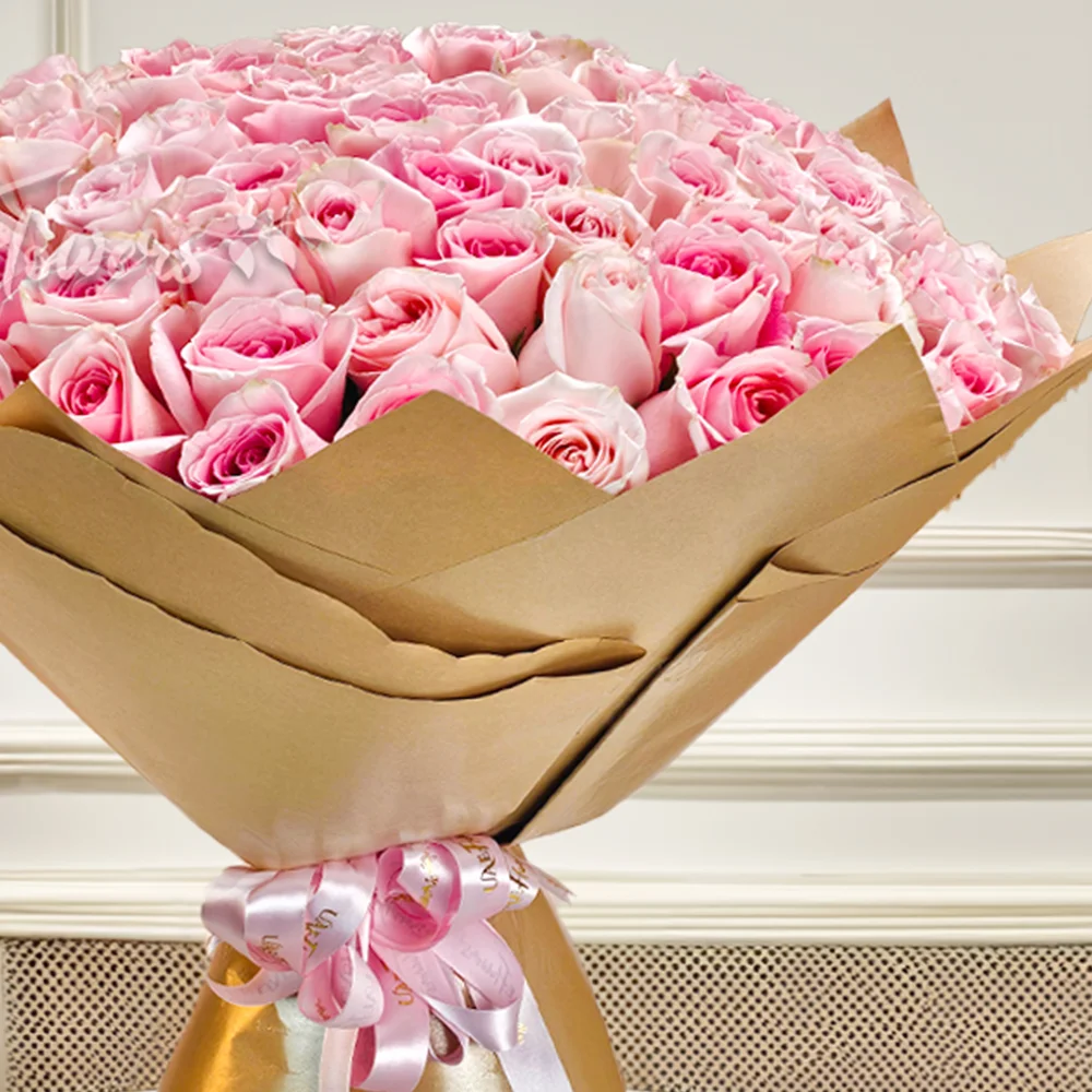 Luxurious bouquet of 100 pink roses, elegantly wrapped in brown paper with a pink satin ribbon. Perfect for anniversaries, birthdays, or heartfelt moments.