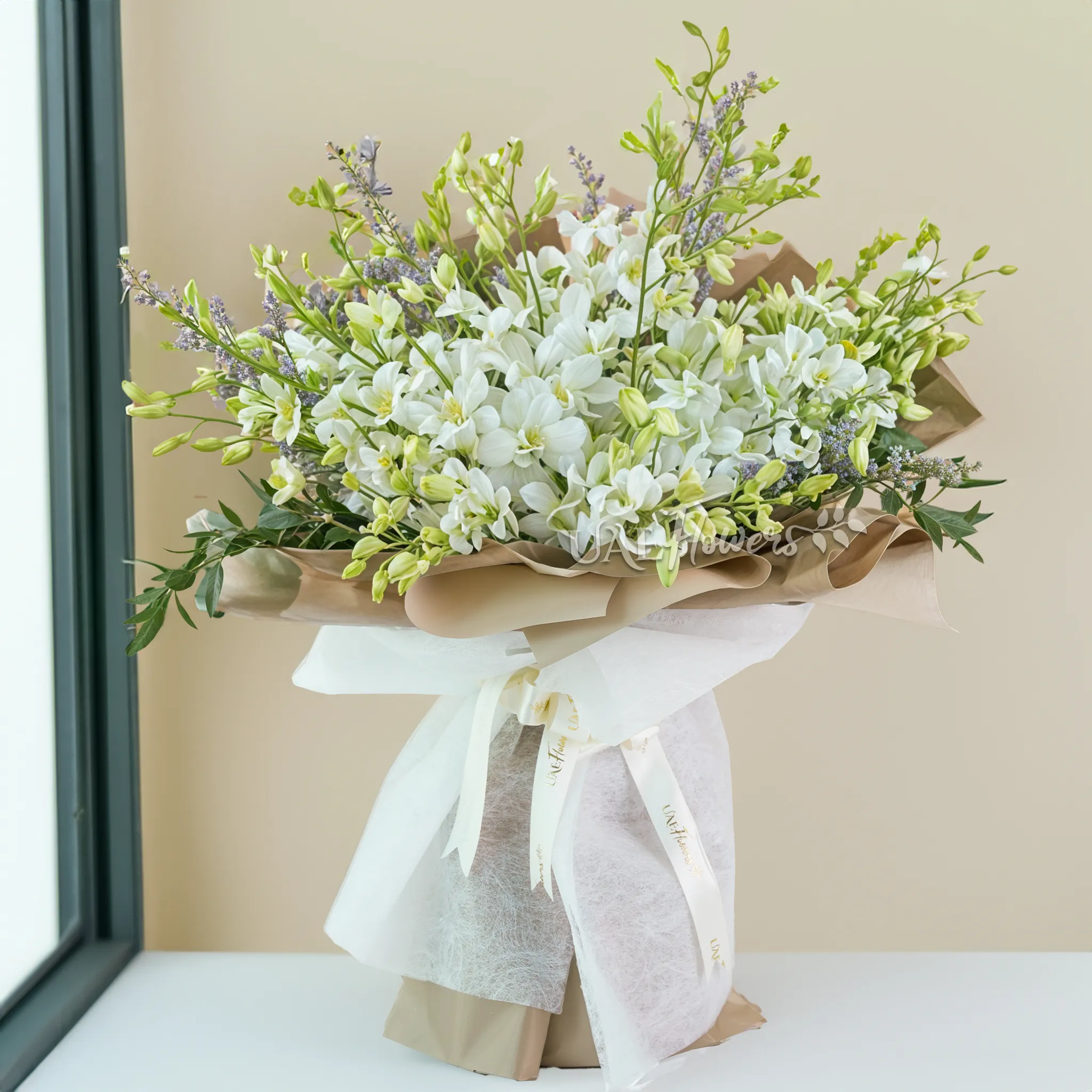 bouquet of 20 white orchids with green fillers and limonium, wrapped in paper and ribbons