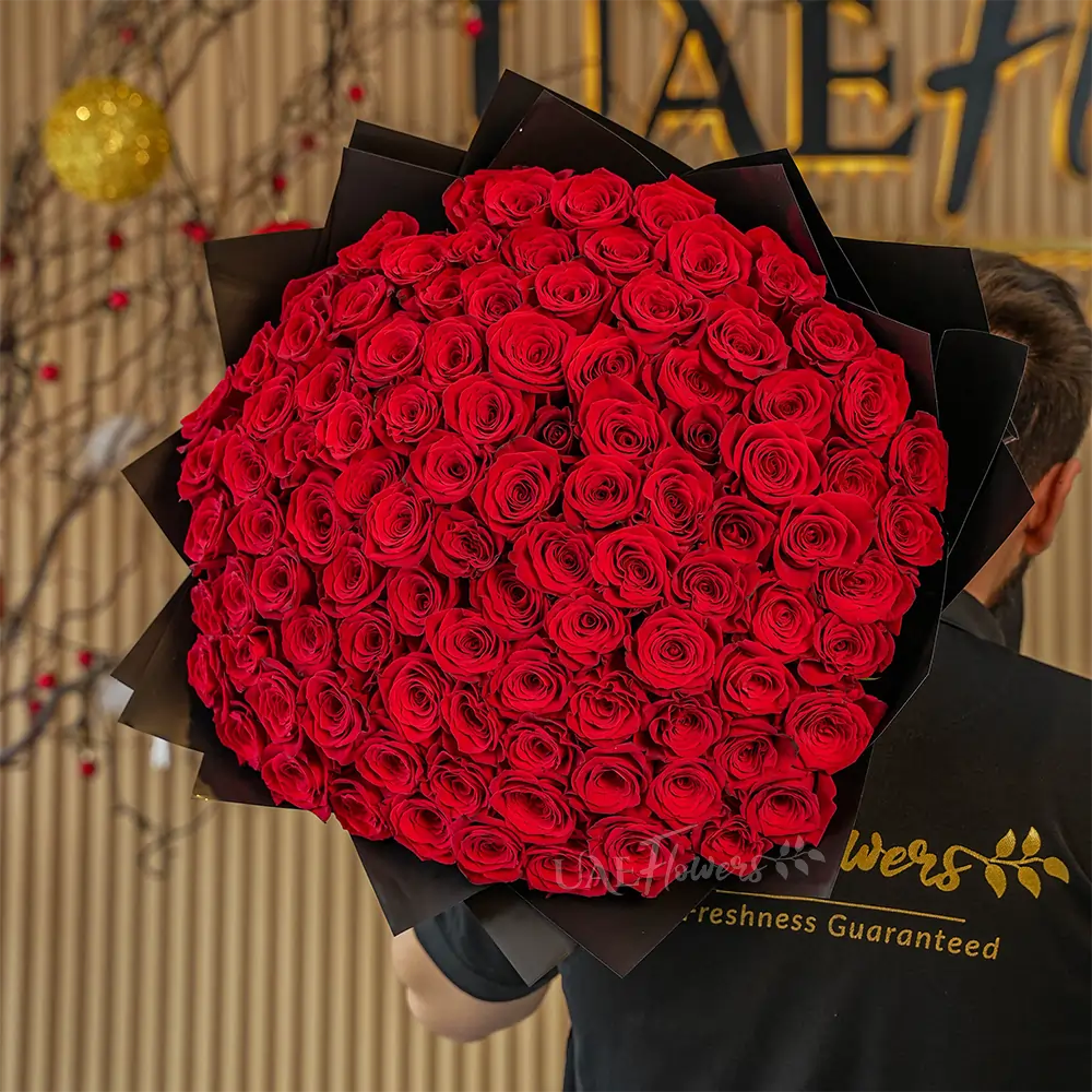 A romantic bouquet of 100 red roses in black wrapping paper tied with black ribbon