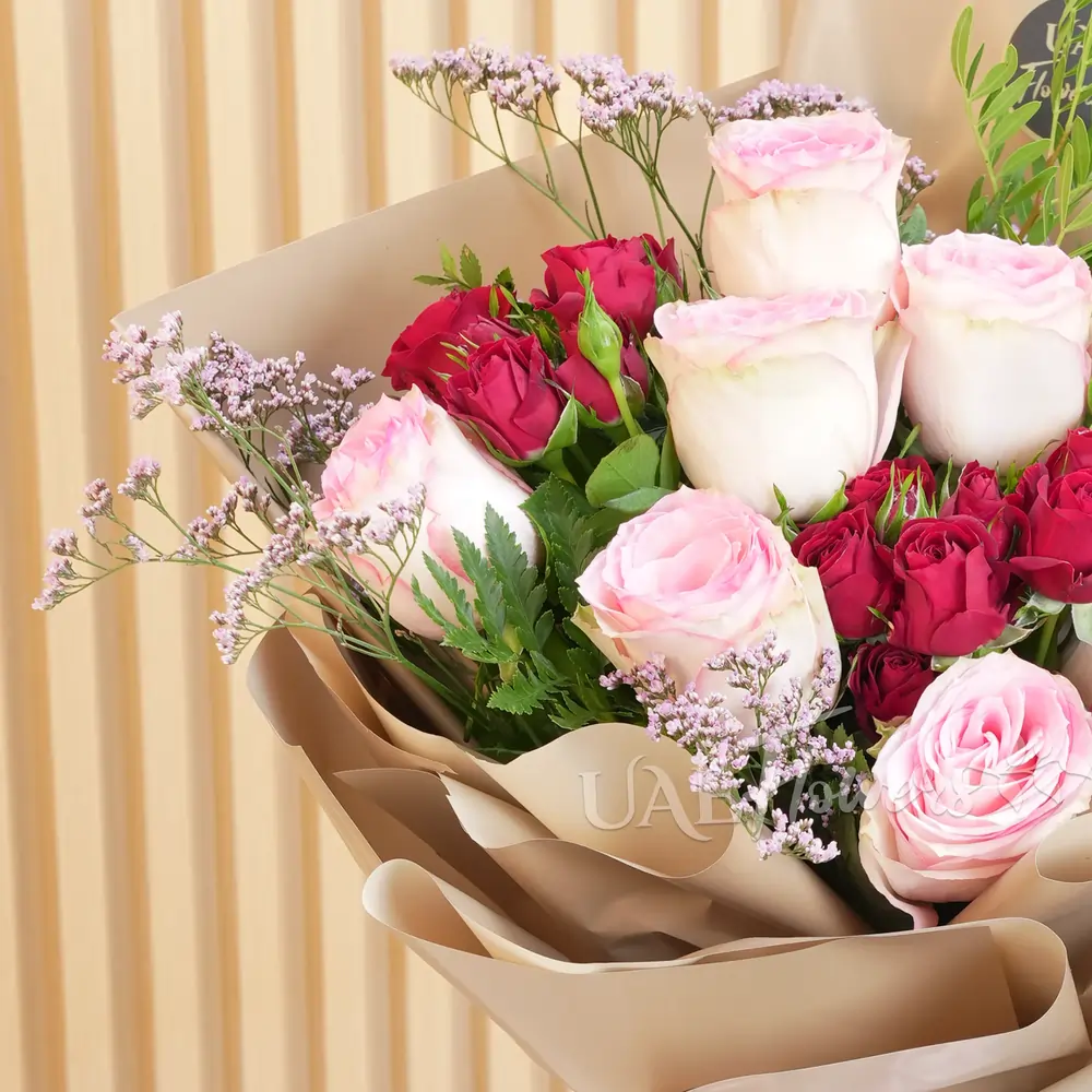 bouquet of 7 pink roses and 3 red spray roses with green and limonium fillers