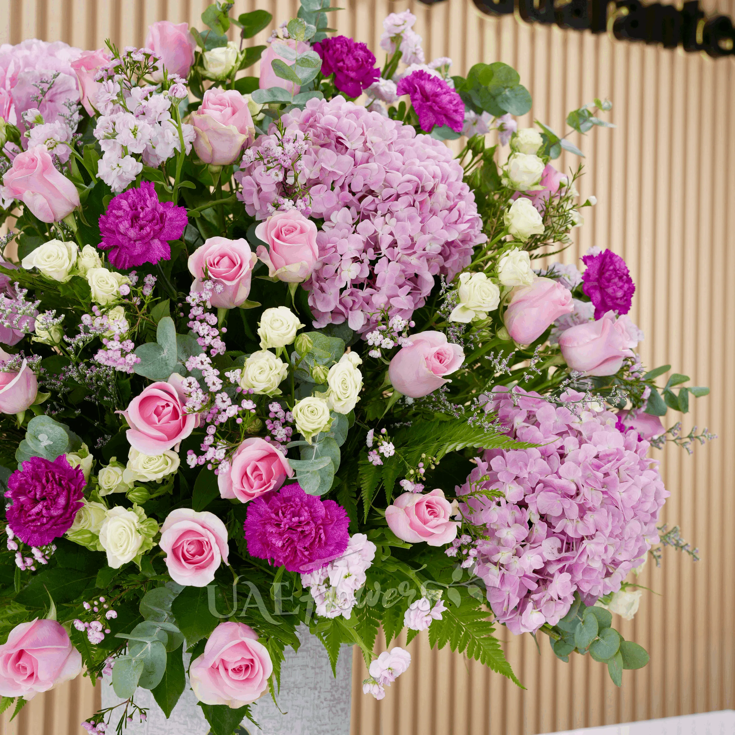 4 pink hydrangeas, 20 pink roses, 5 pink matthiola, and 7 green lisianthus with green fillers in a glass vase
