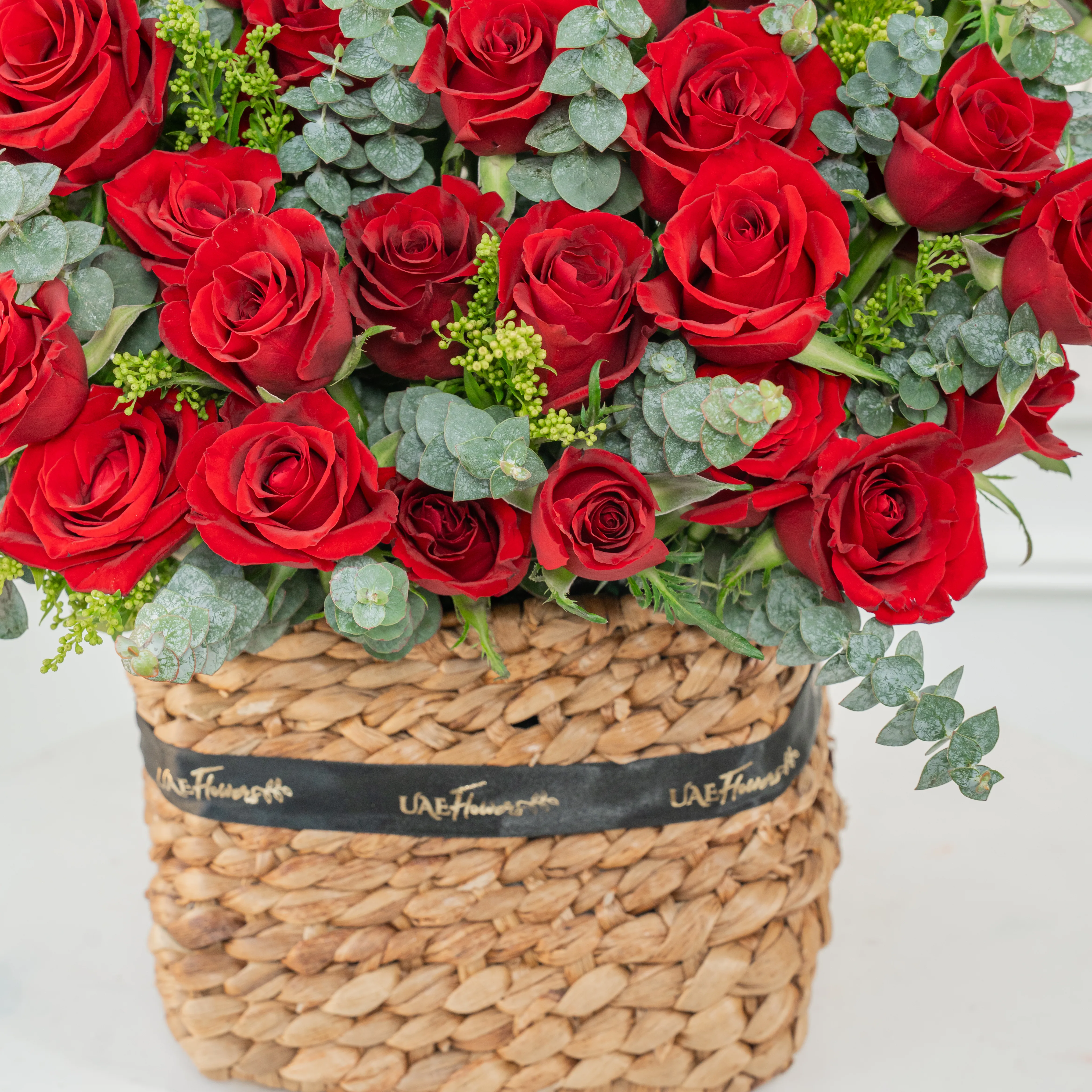 40 red roses with eucalyptus leaf in a square basket.