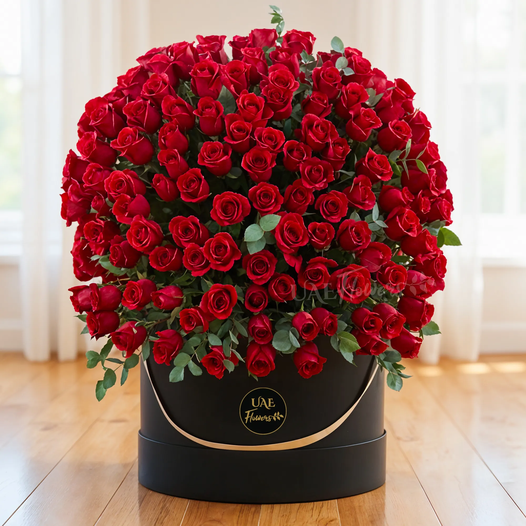 A half-round floral arrangement consisting of 150 red roses with greens, all contained in a black round box