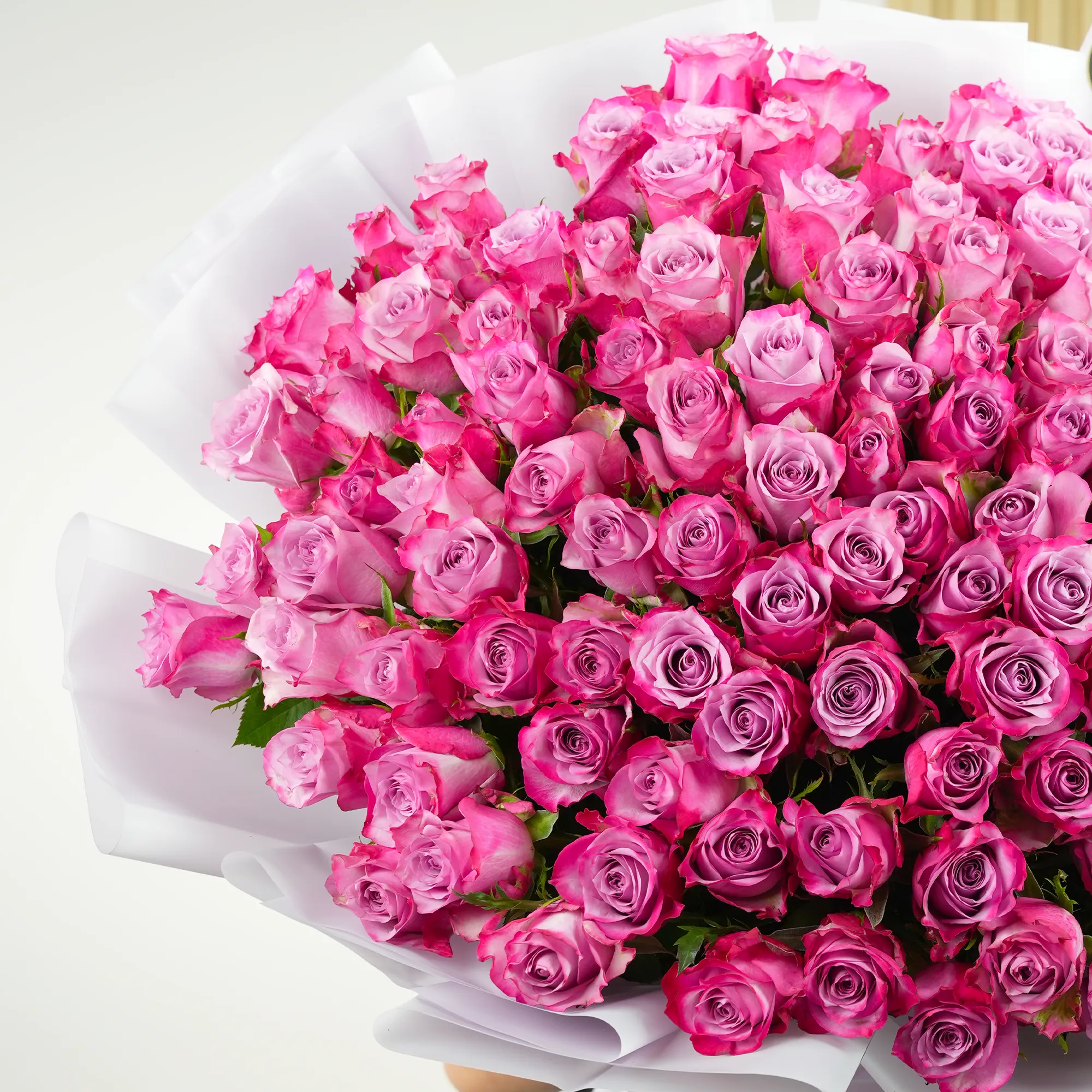 100 purple roses with fillers, wrapped in white paper and tied with ribbons