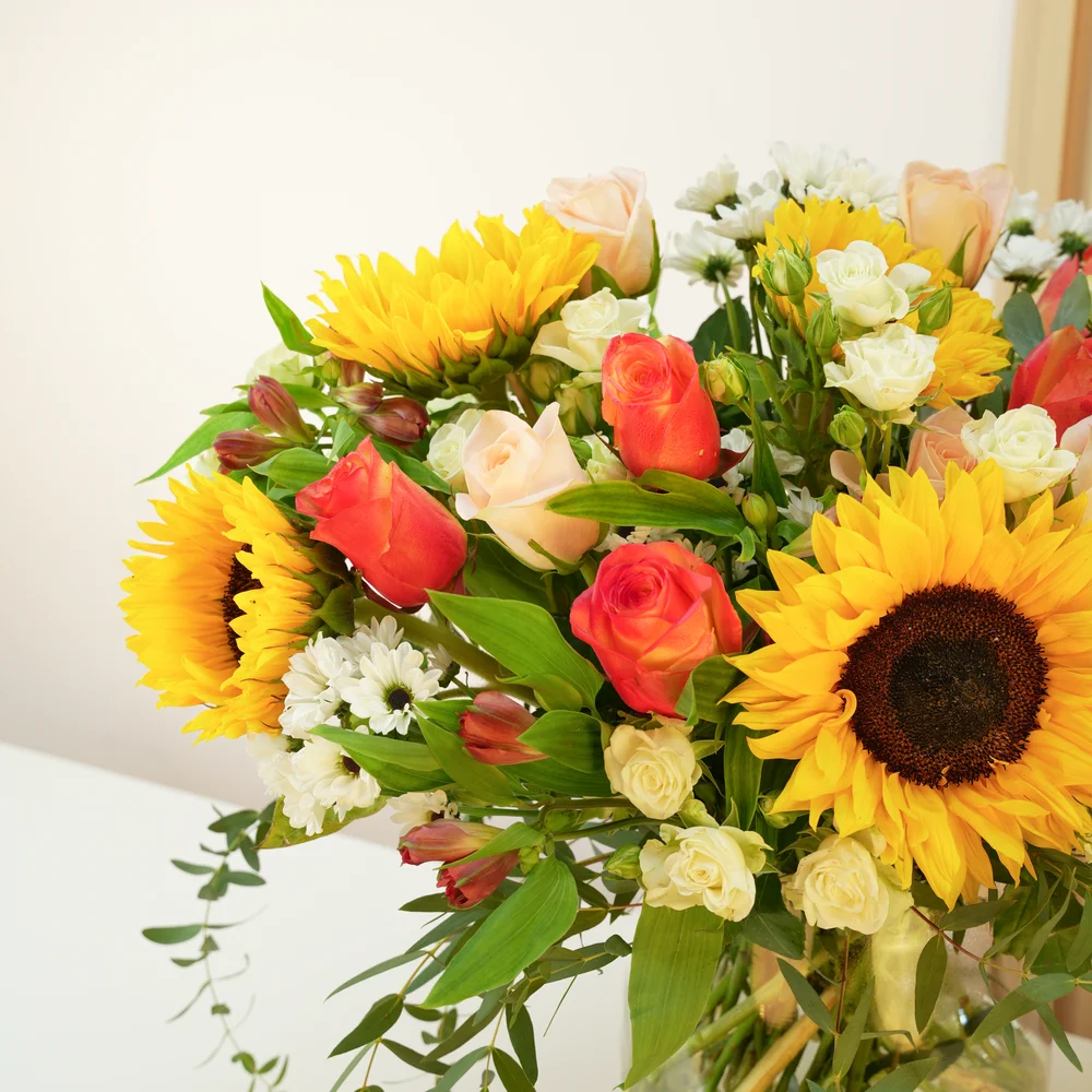 5 sunflowers, 7 orange roses, 7 peach roses, 3 white spray roses, 3 red alstroemerias